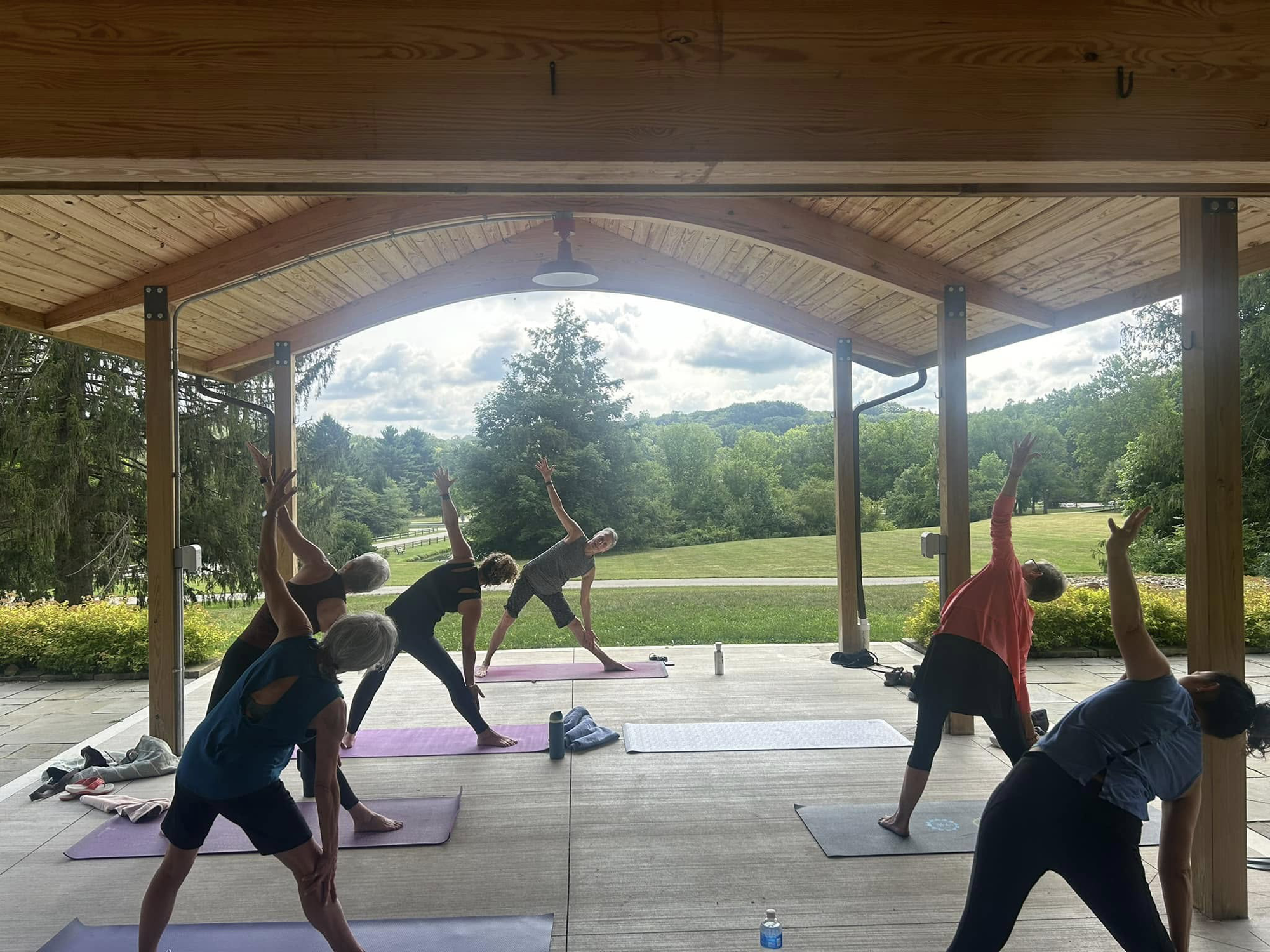 Outdoor group yoga class under wooden pavilion